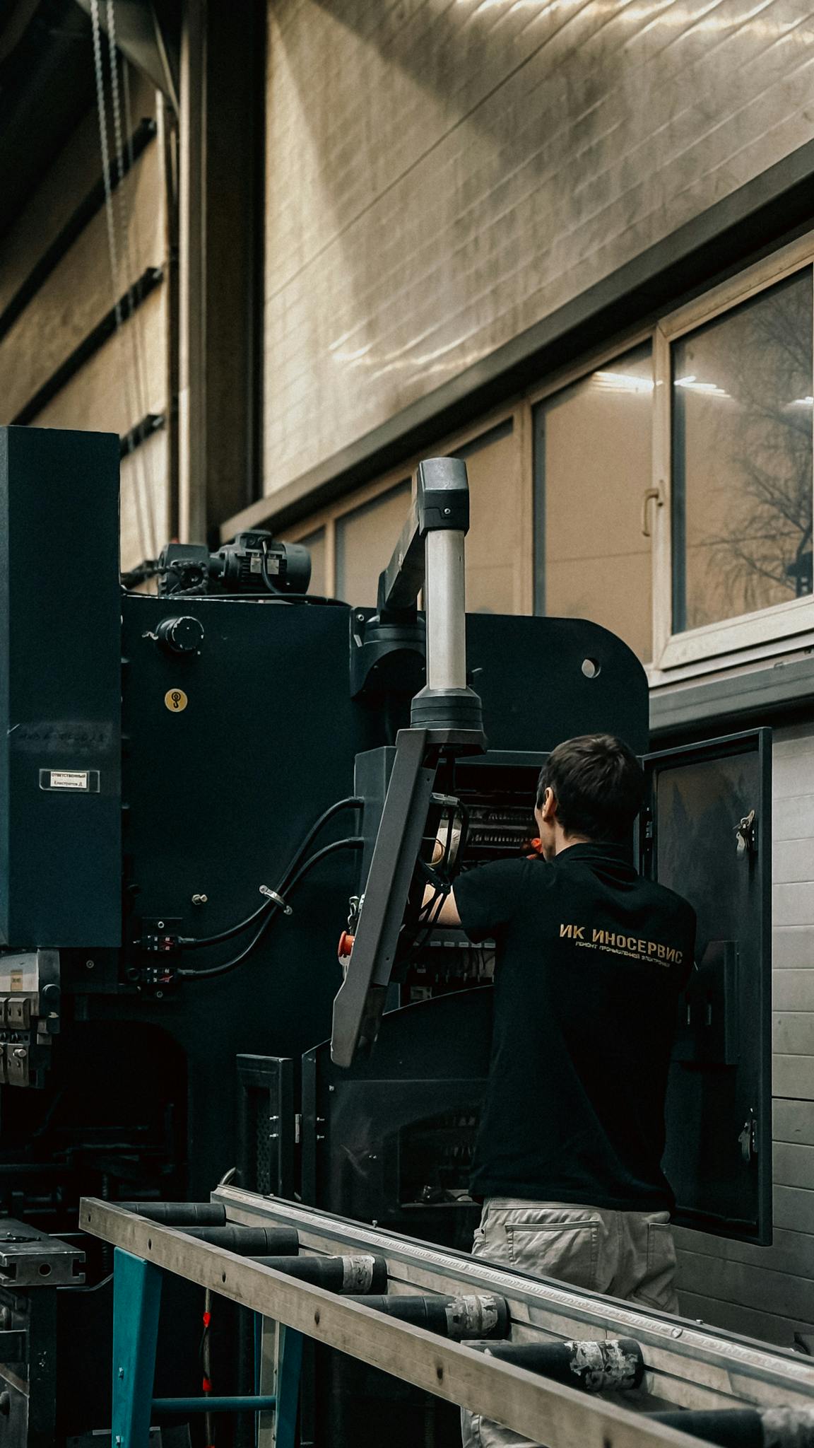 Gallery A worker in an industrial setting operates and adjusts a large machine.
